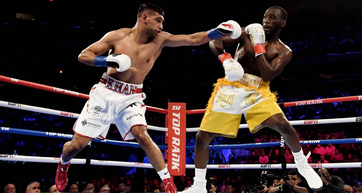 Terence Crawford (yellow trunks) trades punches with Amir Khan